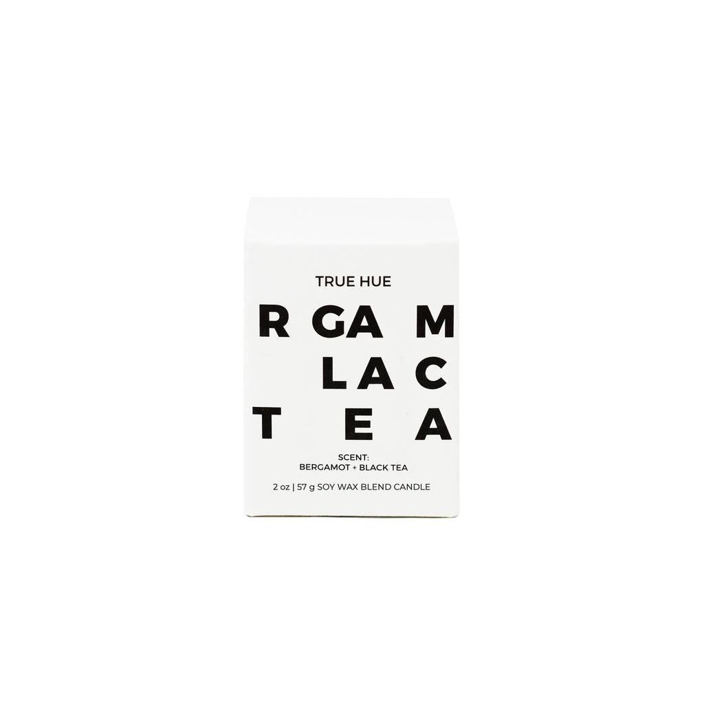 True Hue Bergamot and Black Tea mini candle with a white ceramic holder and a soft flickering flame.