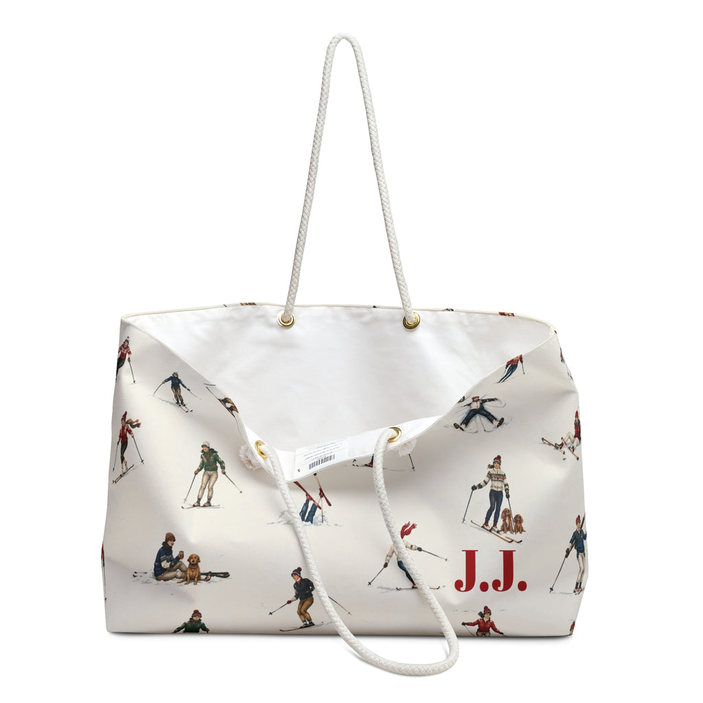 An off-white canvas tote bag with a white rope handle, featuring a vintage-style print of skiers and a red 'J.J.' monogram.