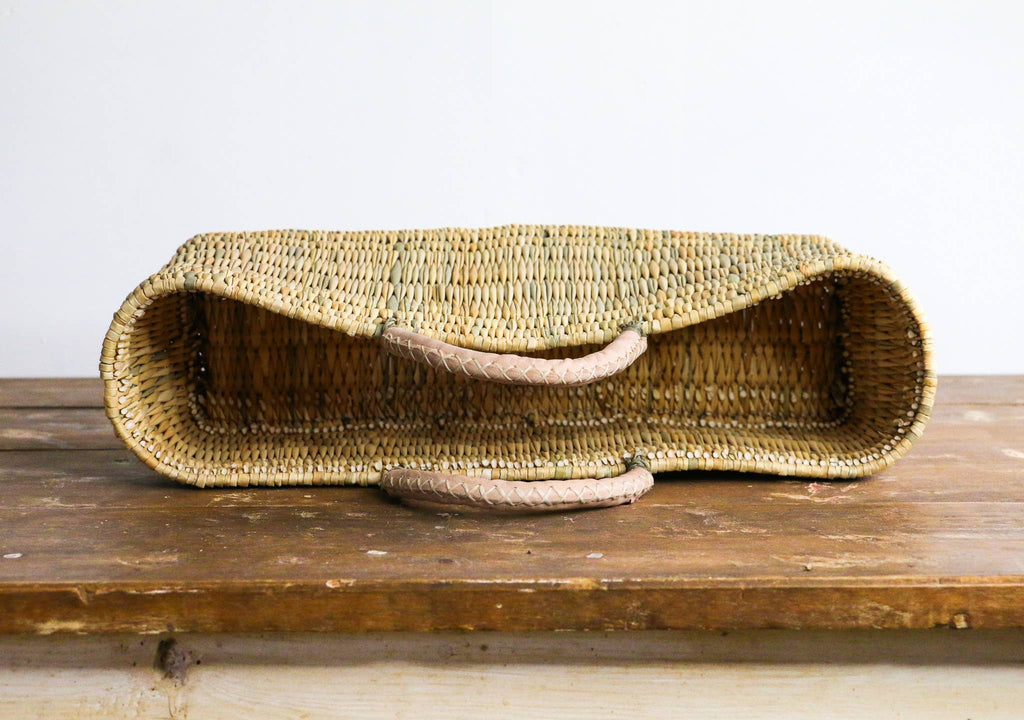 Woven cat bed on a wooden surface with a white background