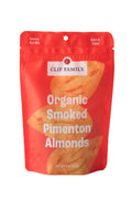 Clif Family Napa Valley smoked pimentón almonds, roasted nuts with smoky paprika flavor, in a clear bowl on a rustic wooden surface.