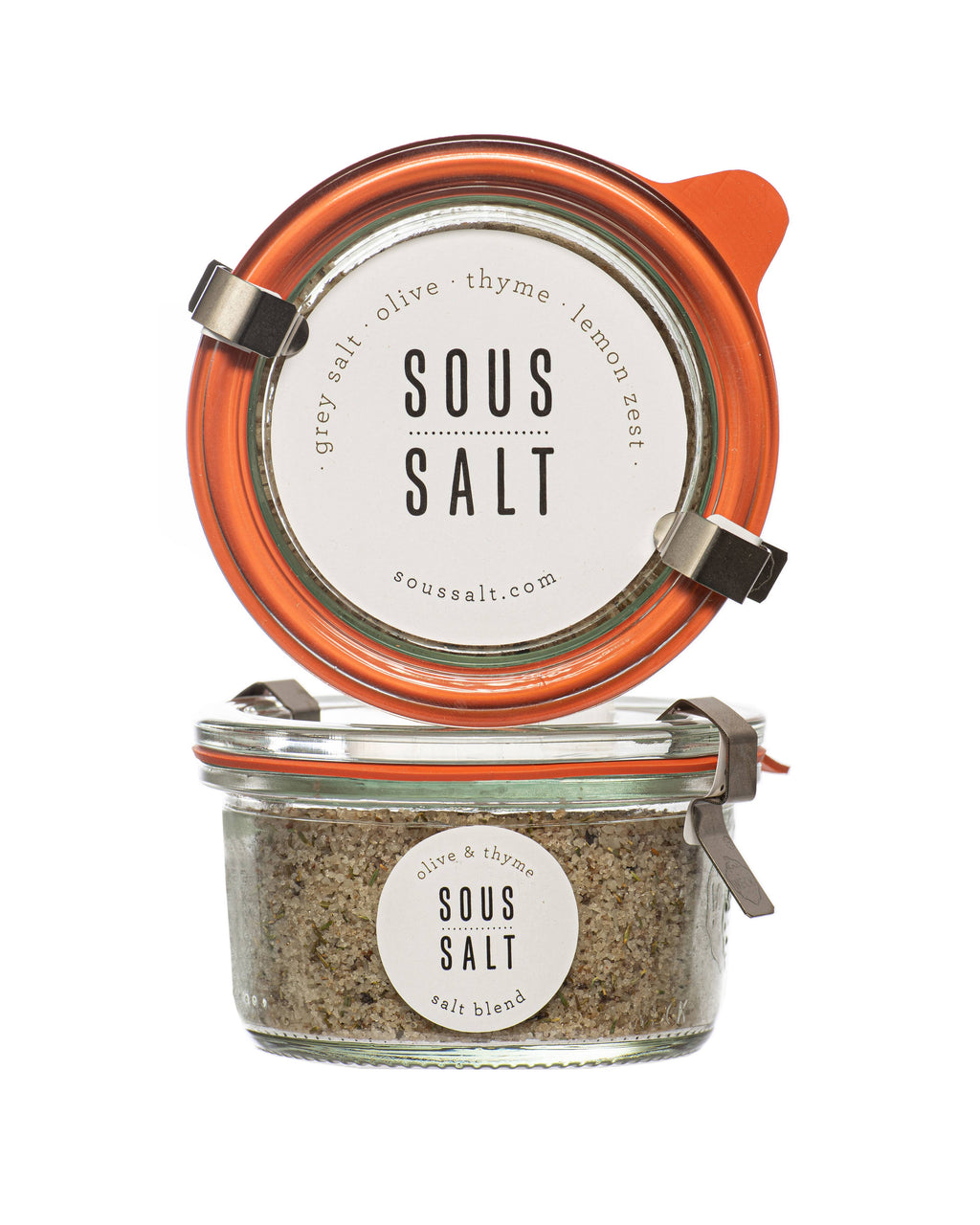 Two glass jars of Sous Salt sea salt with orange lids, one open with its lid propped up to show the white label, and one closed showing the salt blend inside.