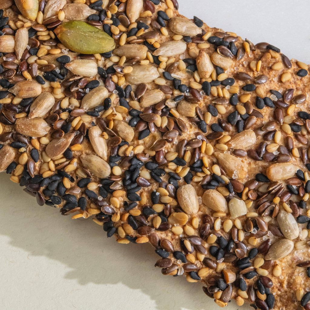 Three seeded olive oil flatbreads from Potters Table snacks, crispy and golden with visible sesame and poppy seeds on top.