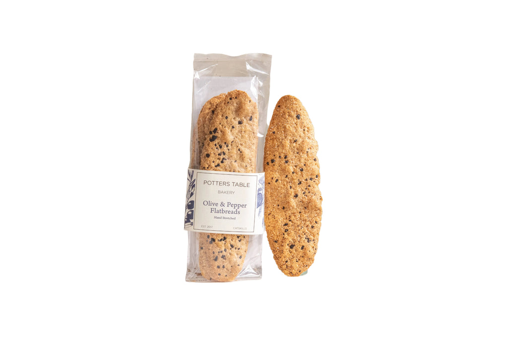 Potters Table cured olive and cracked pepper flatbreads crackers on a wooden serving board.