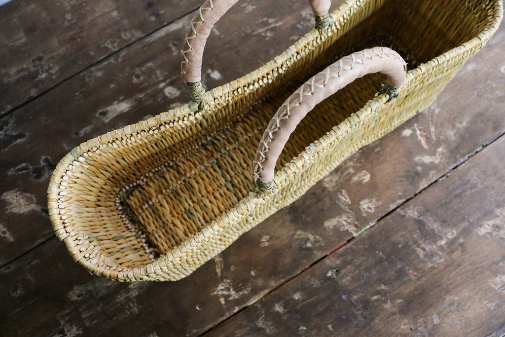 Woven basket with pink handles on a wooden surface