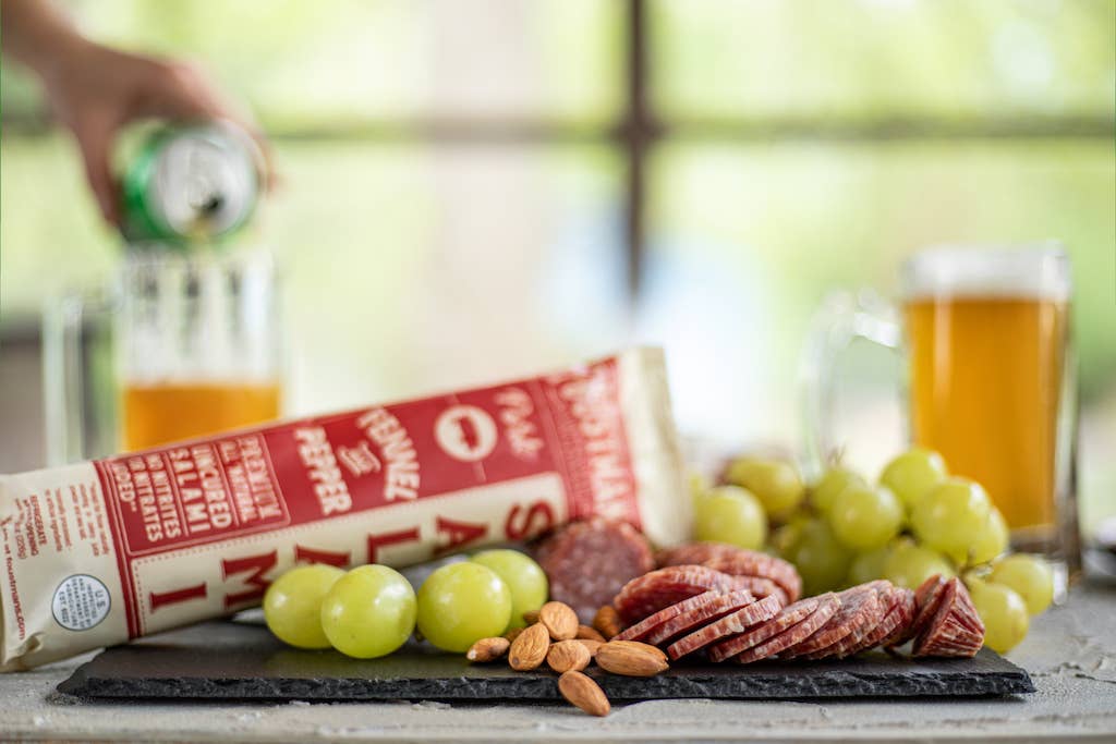Platter of salami, grapes, and almonds with a can of beer on a blurred background