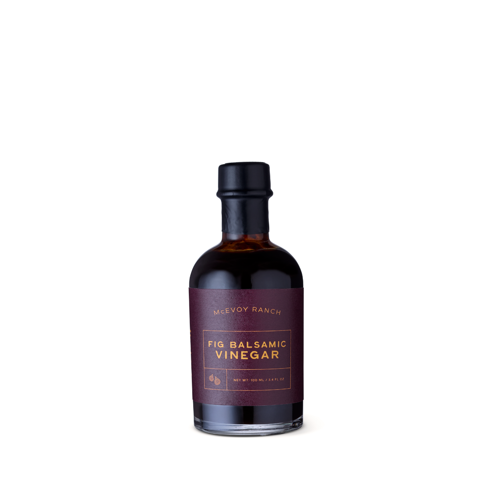 A bottle of McEvoy Ranch Fig Balsamic Vinegar with a dark burgundy label and black cap, centered on a plain white background.