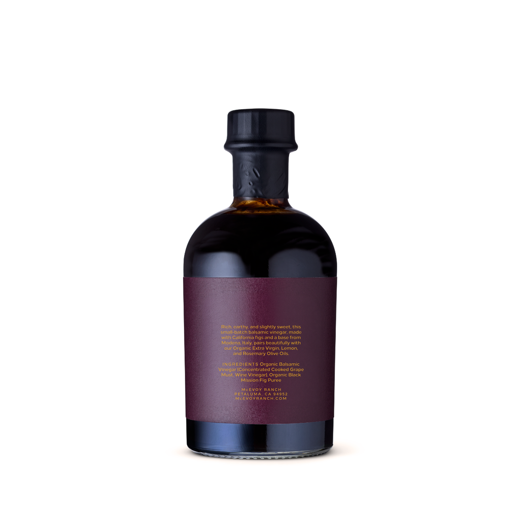 A dark glass bottle with a black cap and a deep burgundy label featuring gold text, shown against a plain white background. McEvoy Ranch 