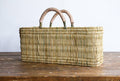 Woven basket with handles on a wooden surface