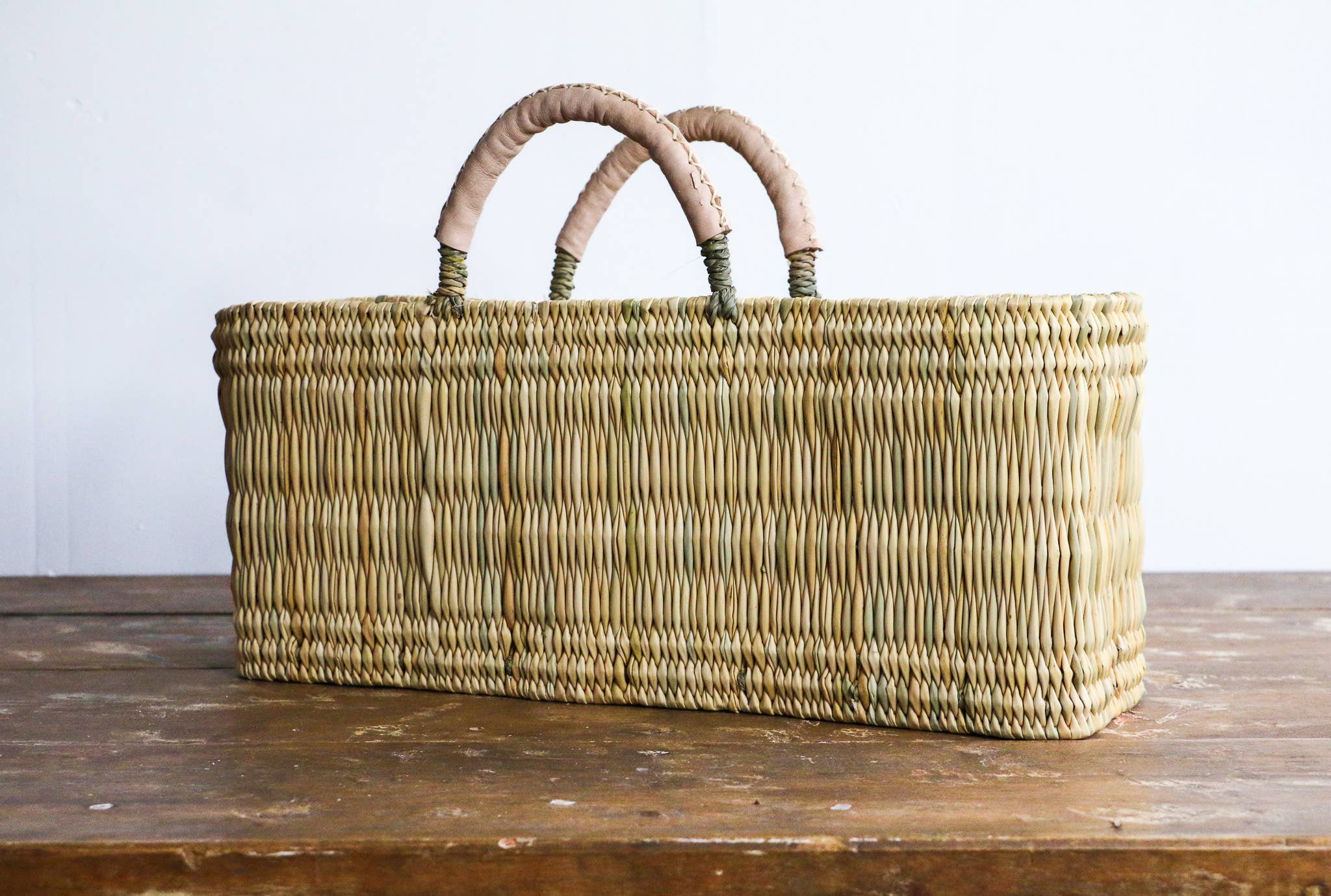 Woven basket with handles on a wooden surface