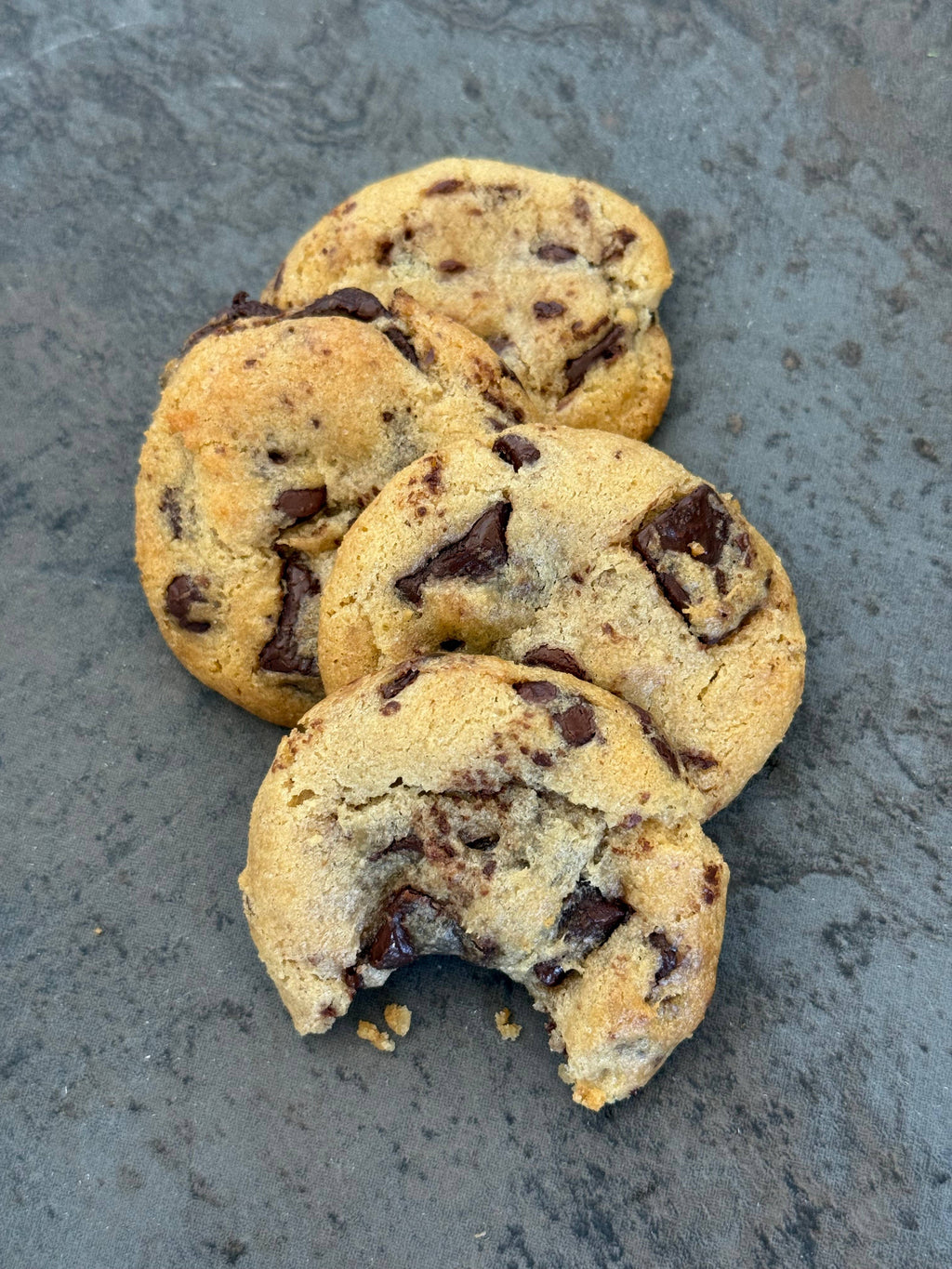  Sweet Sydney's chocolate chunk cookies on a marble surface with a tiled wall background