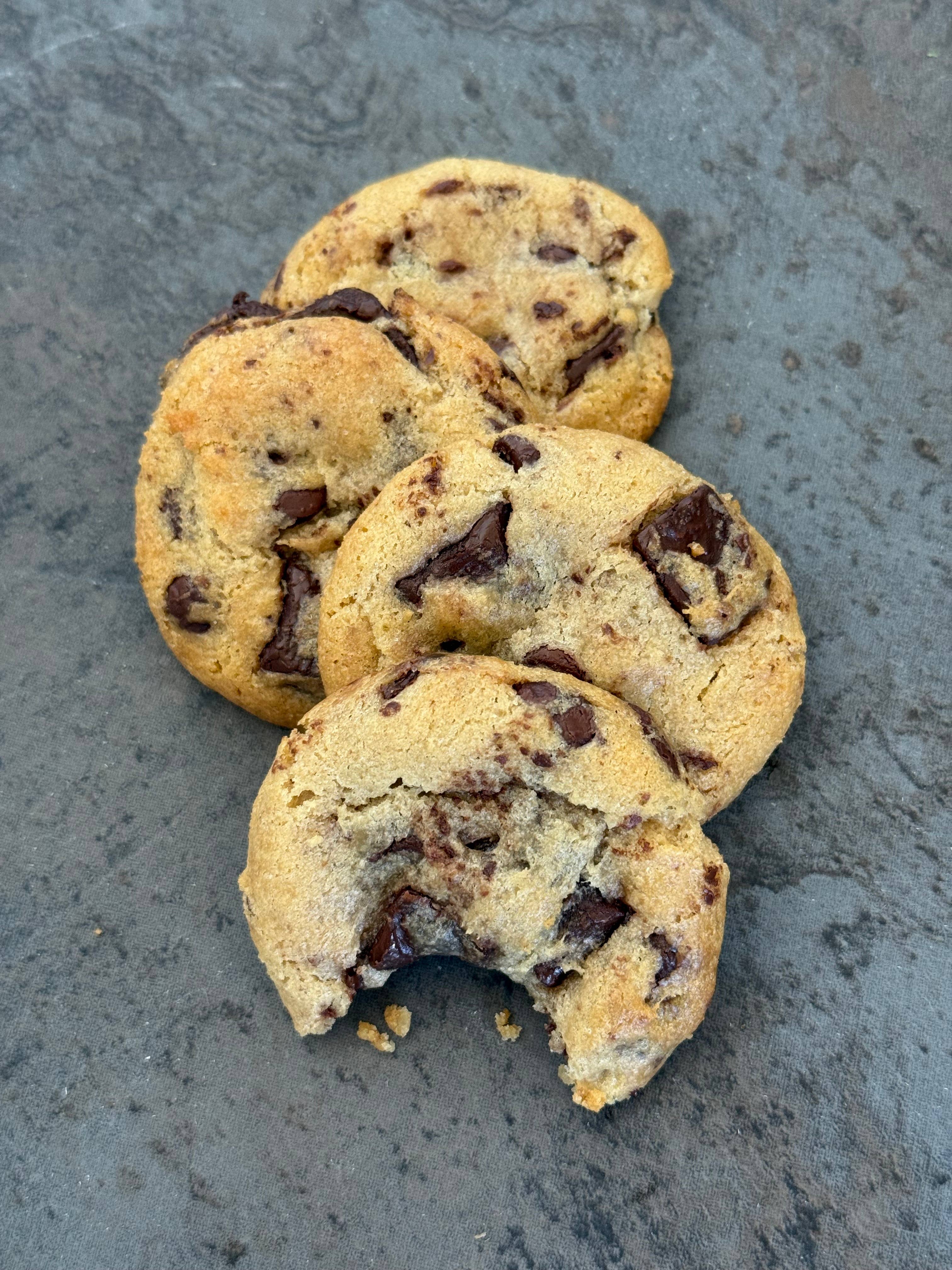  Sweet Sydney's chocolate chunk cookies on a marble surface with a tiled wall background