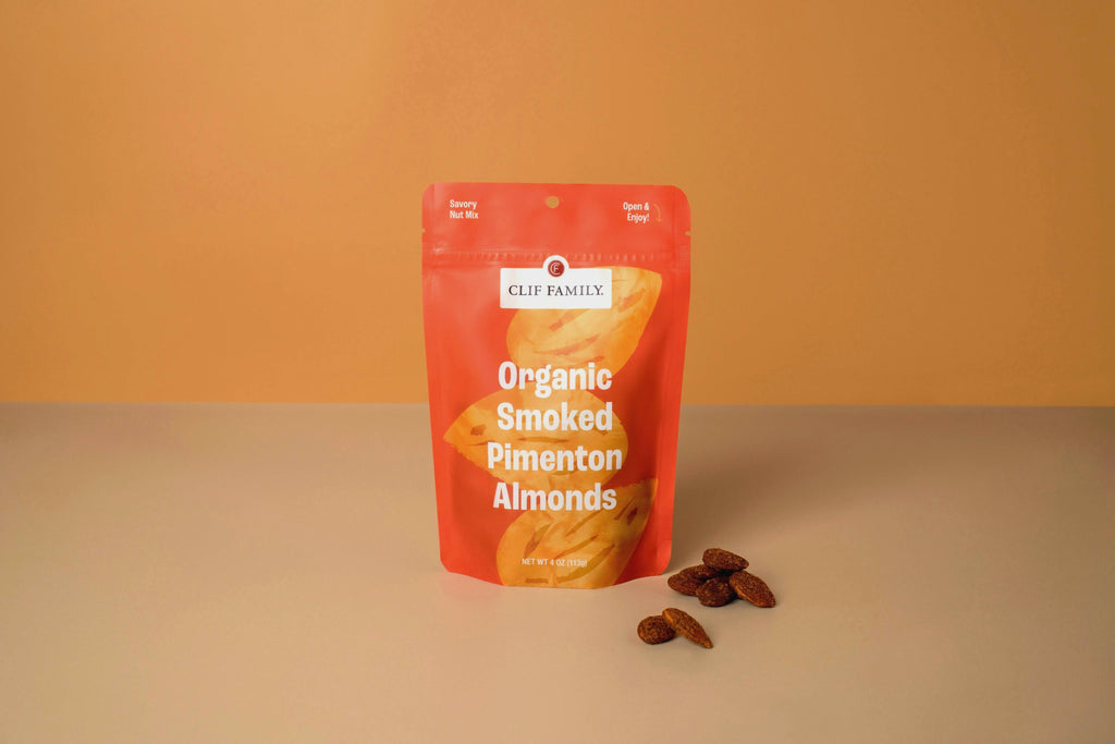 Clif Family Smoked Pimenton Almonds in a bowl, roasted nuts with smoky pimenton seasoning, on a rustic wooden surface.
