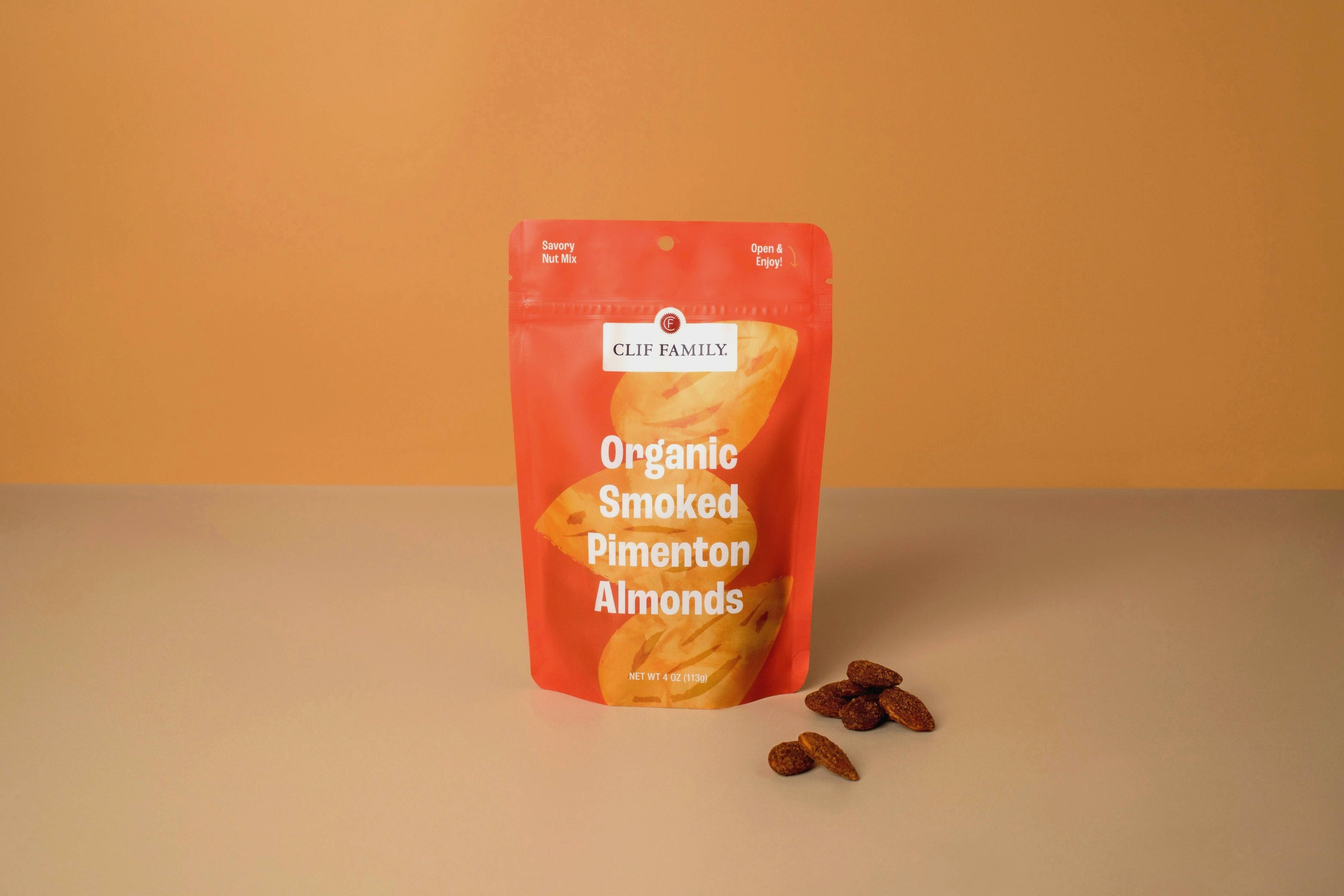 Clif Family Smoked Pimenton Almonds in a bowl, roasted nuts with smoky pimenton seasoning, on a rustic wooden surface.