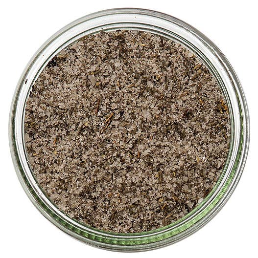 A top-down view of coarse sea salt granules inside a clear glass jar, set against a plain white background.