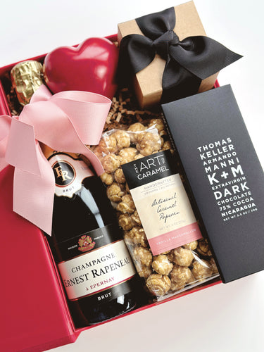Gift basket with champagne, chocolate, and candy in a decorative box.