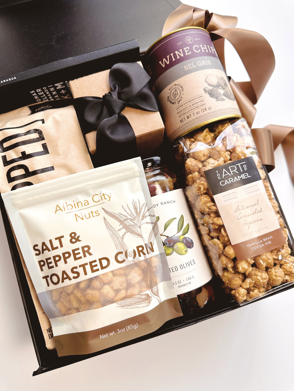 Black and tan gift box from Poppins & Post featuring a stylish, elegant packaging with assorted treats inside.