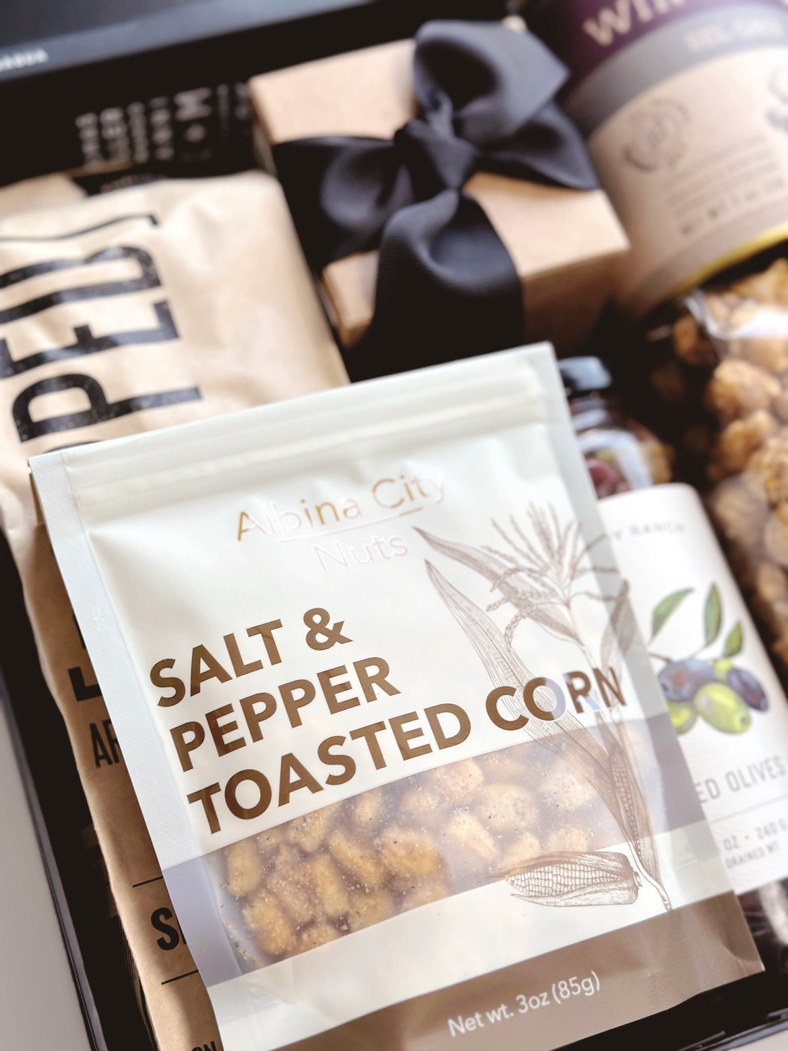 Black and Tan gift box from Poppins & Post with assorted chocolates or treats arranged inside.