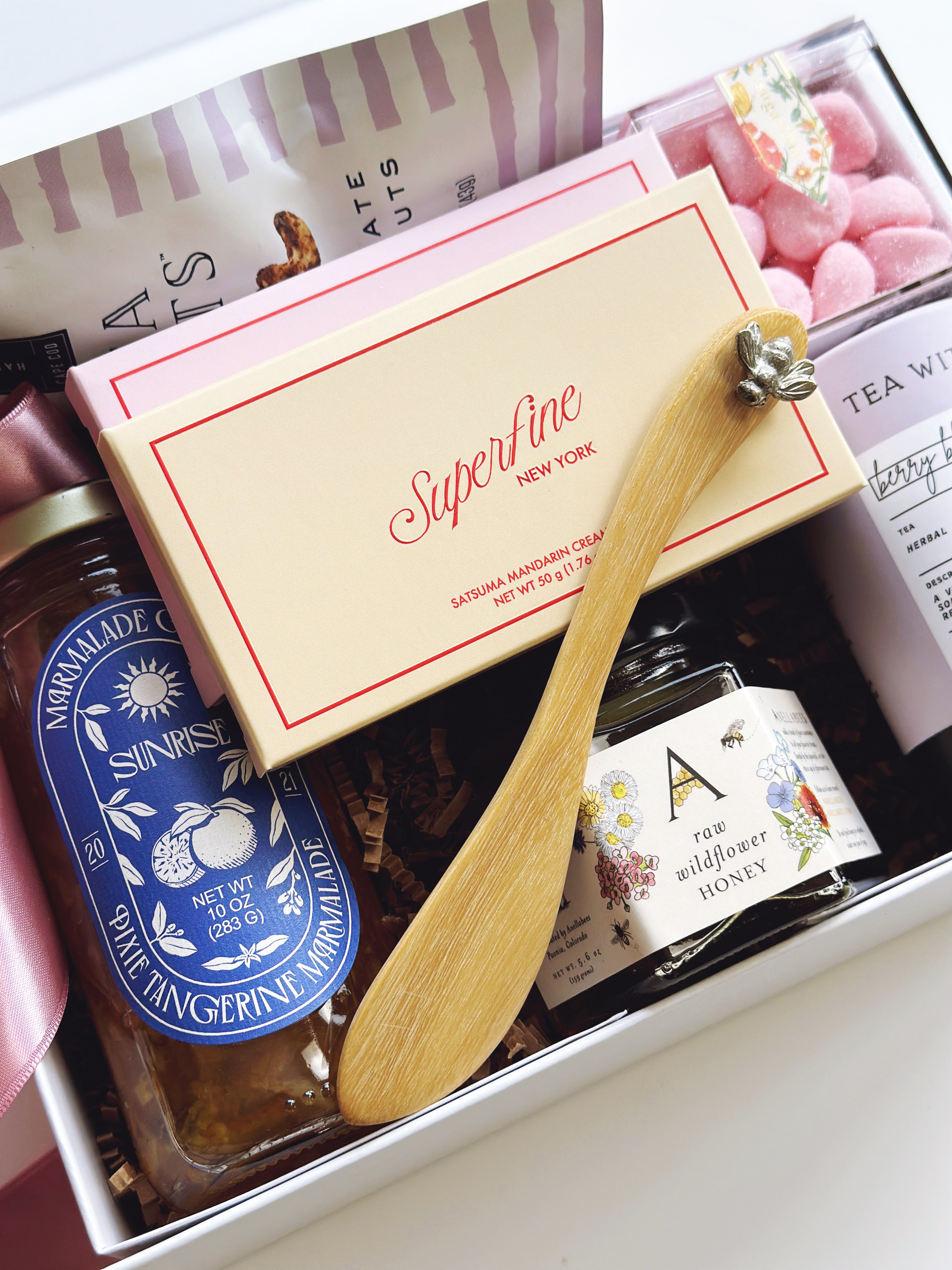 Gift box with a wooden spoon, jar of honey, and other items on a white background