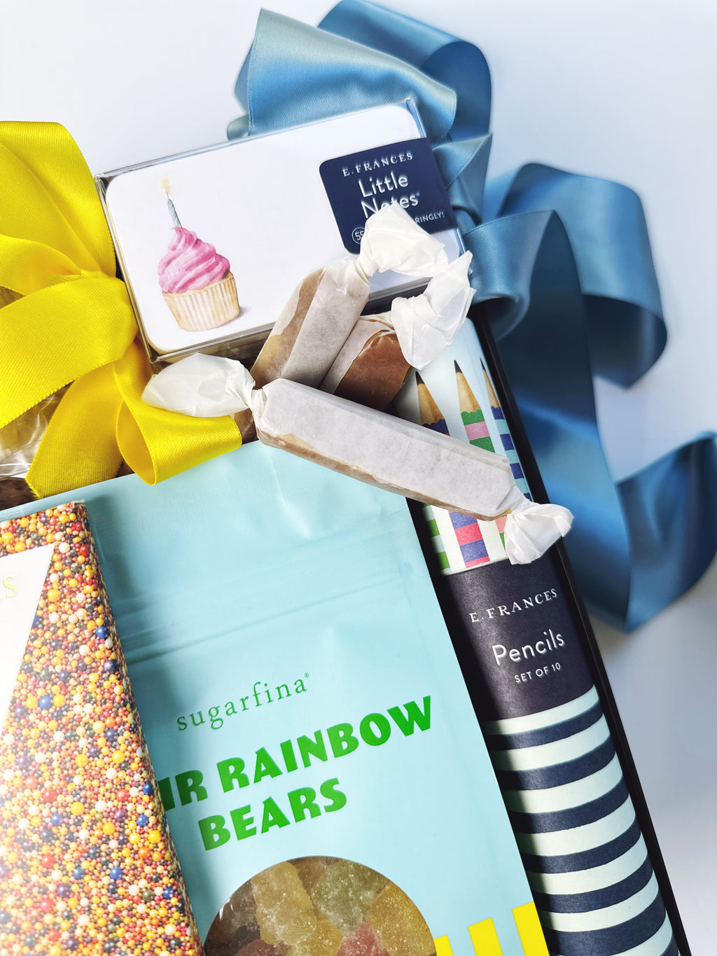 A gift basket arrangement featuring a light blue bag of sugarfina Rainbow Bears.