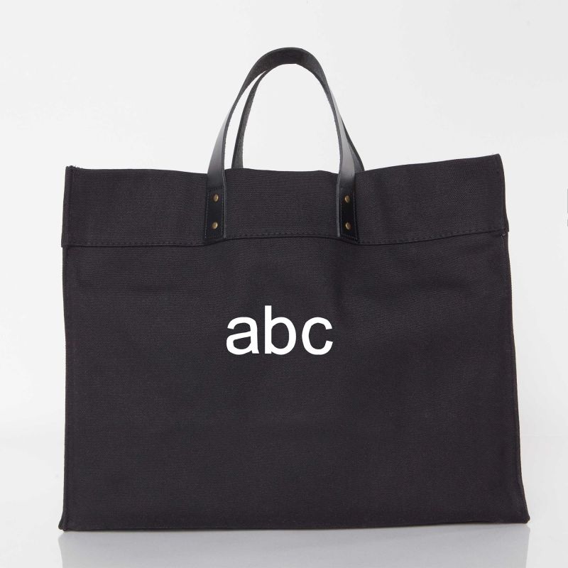 A black canvas tote bag with black leather handles and a white 'abc' logo printed on the front, set against a plain white background.