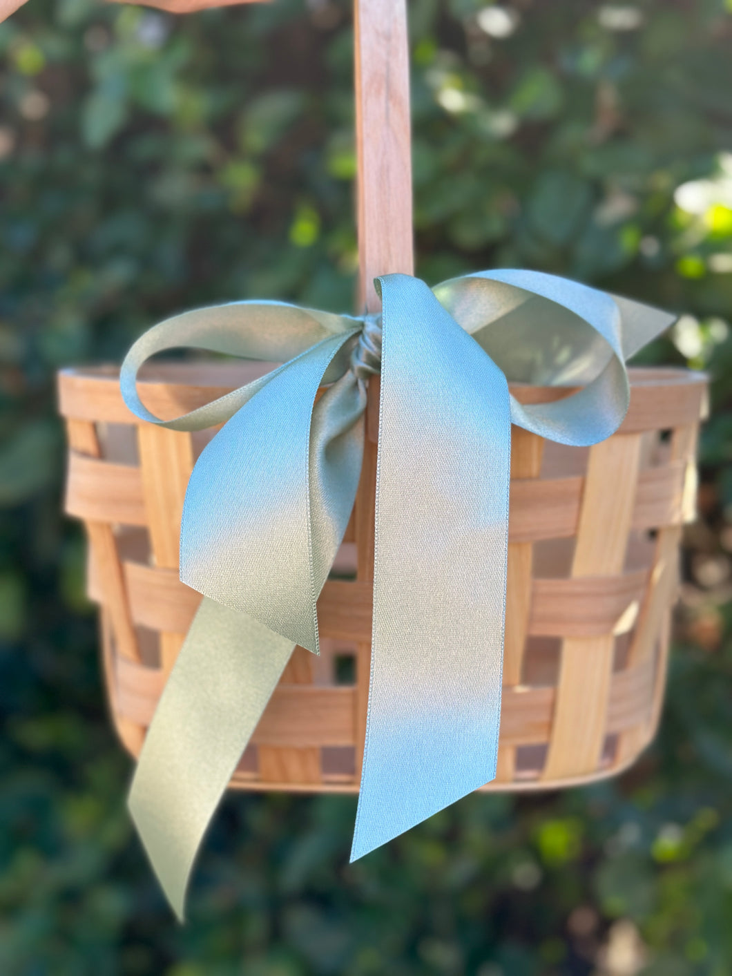 Wooden basket with a decorative ribbon against a blurred green background