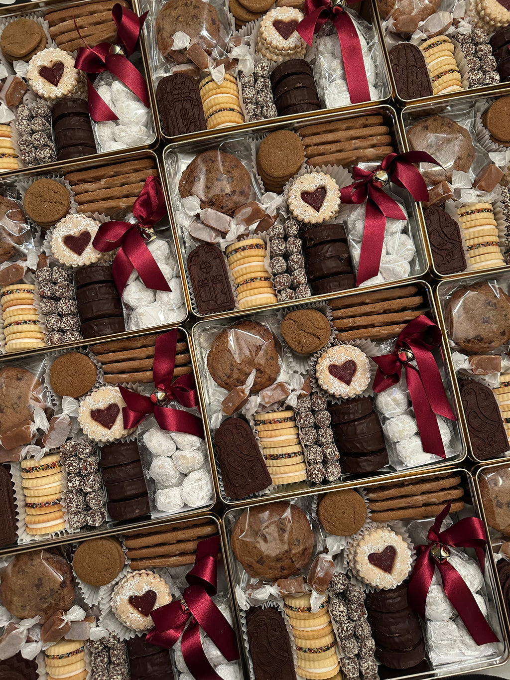 Rows of holiday tins filled with assorted Christmas cookies.
