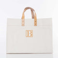 A large canvas tote bag in off-white with light tan leather handles and a matching tan square logo patch featuring a stylized letter B on the front, set against a plain white background.