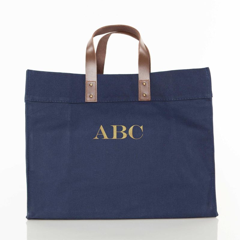 Navy blue tote bag with brown leather handles on a white background