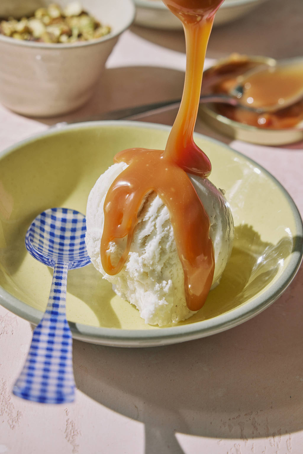 Ice cream scoop with caramel sauce on a plate with a checkered spoon