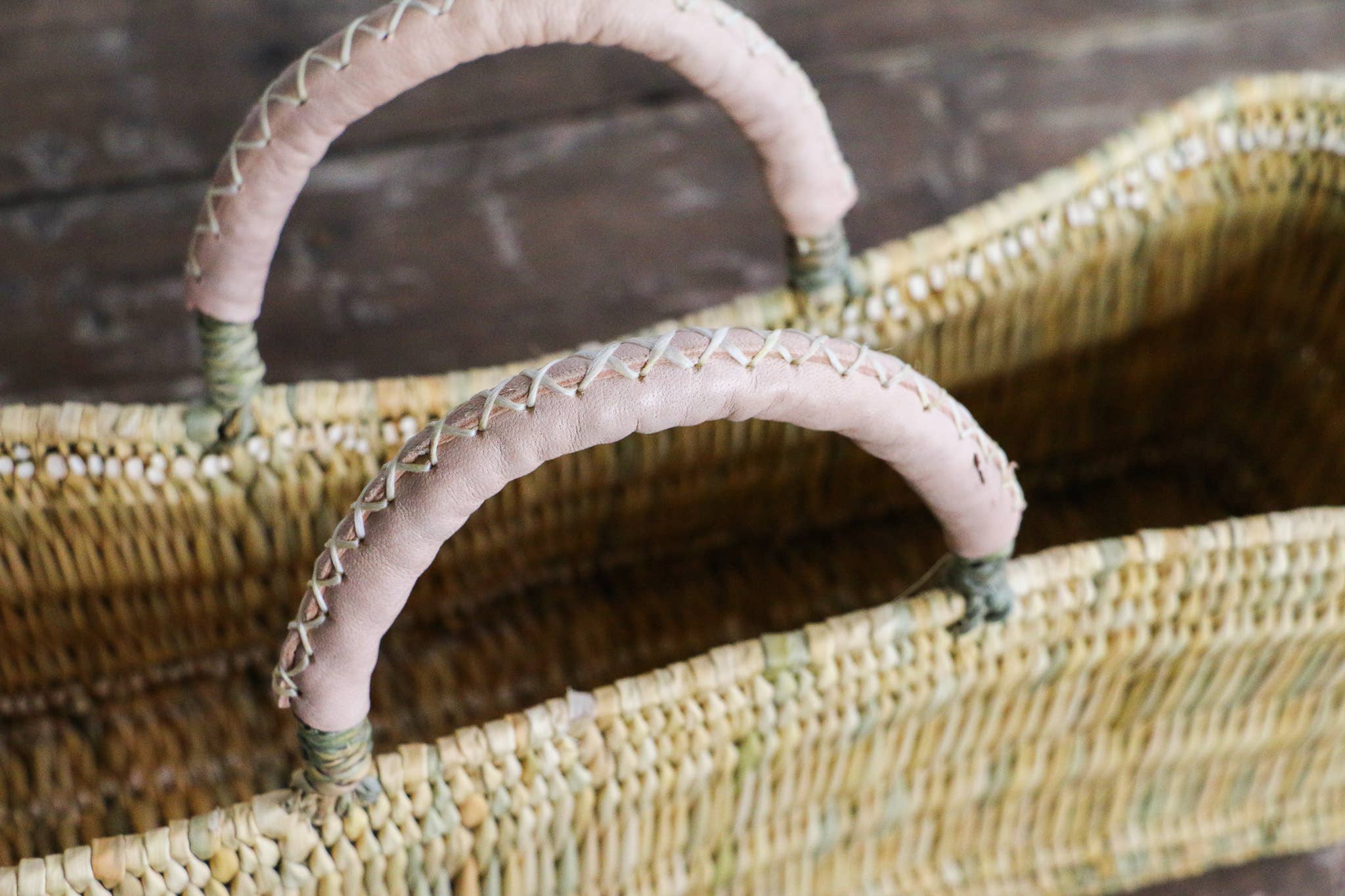 Wicker basket with pink handles on a wooden surface