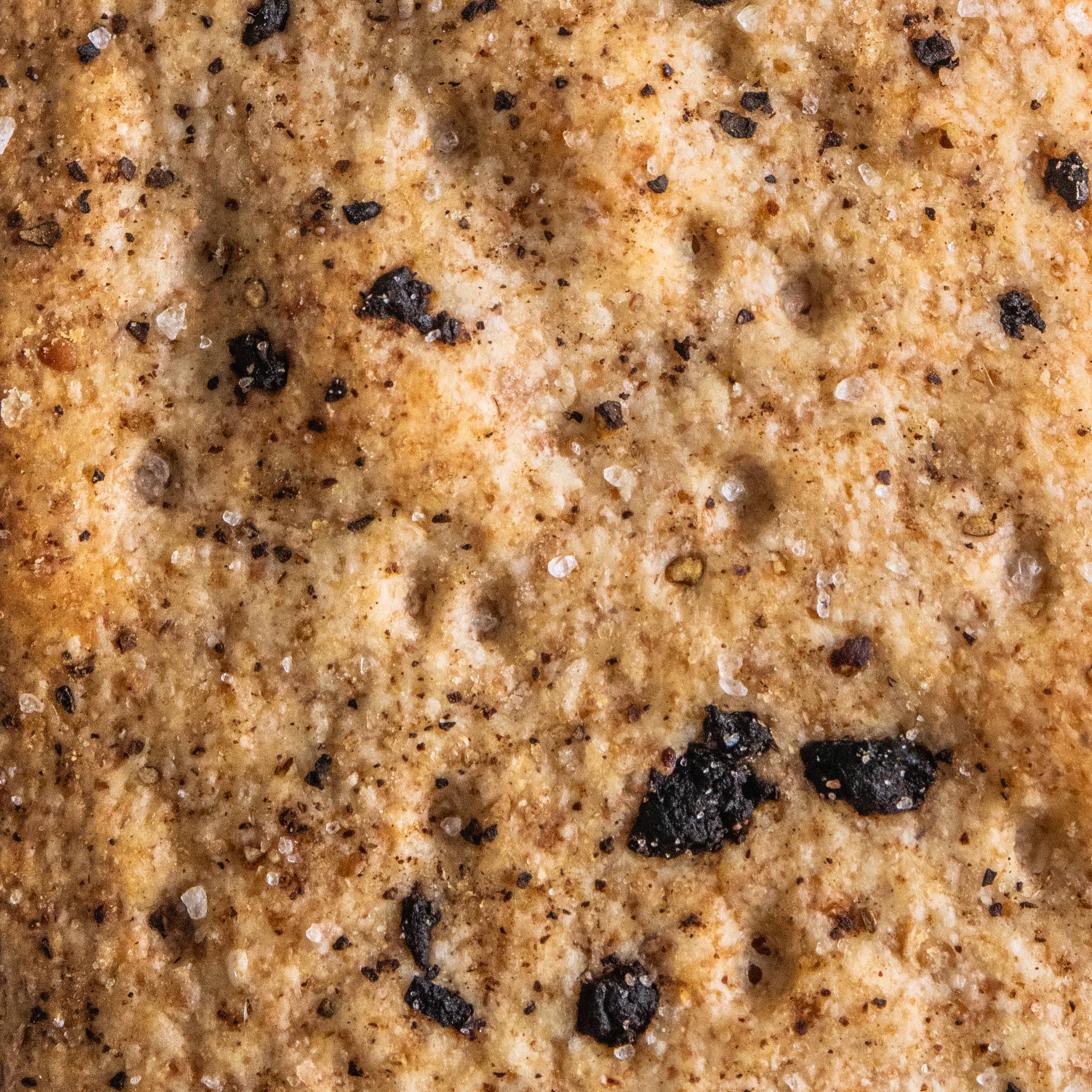 Potters Table cured olive and cracked pepper flatbreads crackers with visible olives and cracked pepper on a rustic surface.