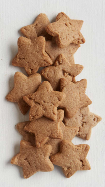 A pile of star-shaped gingerbread cookies on a light off-white background.