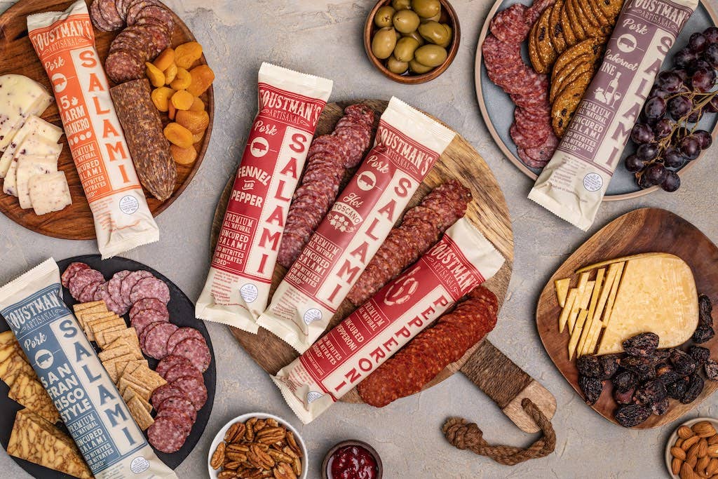 Assorted Foustman's Salami packages with a variety of snacks and meats on a table.