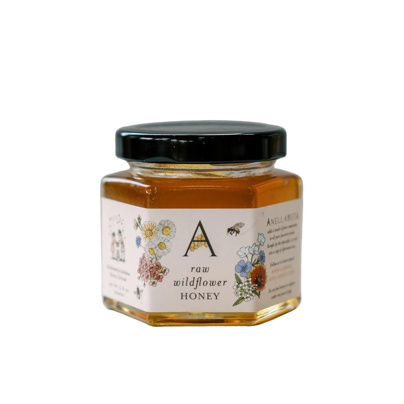 Glass jar of raw wildflower honey from Anellabees, showcasing golden honey with wildflower blossoms in the background.
